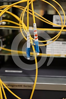 Yellow optical fiber network cable with blue connectors with the equipment on the background