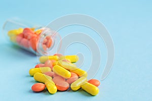 Yellow and orange capsules from glass bottle on blue background. copyspace for text. Epidemic, painkillers, healthcare, treatment