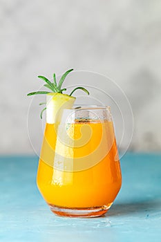 Yellow orange cocktail with melon and mint in glass on blue concrete background, close up