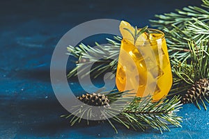 Yellow orange cocktail with tangerine and rosemary in glass on dark blue concrete background decorated pine branches with cones,