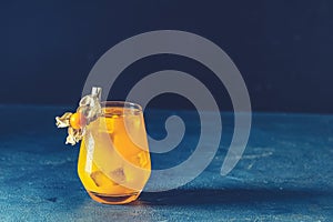 Yellow orange cocktail with tangerine and rosemary in glass decorated Physalis peruviana on dark blue concrete background , close