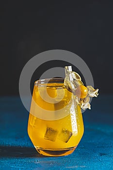 Yellow orange cocktail with tangerine and rosemary with ice in glass on dark blue concrete background , close up. Christmas and