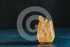 Yellow orange cocktail with tangerine and rosemary with ice in glass on dark blue concrete background , close up. Christmas and