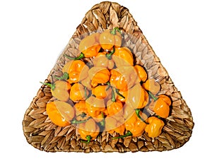 Yellow orange ripe habanero hot chili peppers on a wooden plate