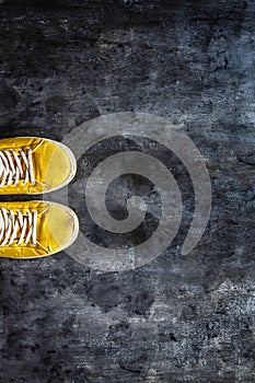 yellow-orange sneakers with untied laces on a dark concrete background. Copy space. Top view