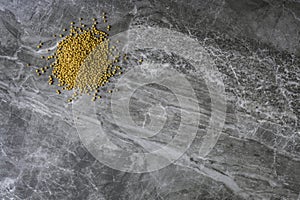 Yellow organic dried mustard seeds on a marble kitchen worktop background