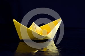 Yellow Origami Boat on Wet Black Background