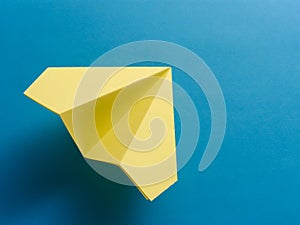 Yellow origami fighter jet on blue background