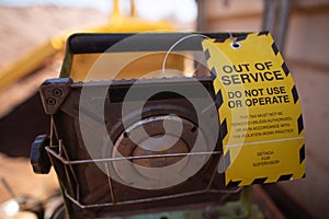 Yellow out of service tag attached on faulty damage defect of light at construction site Perth, Australia