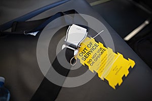 Yellow out of service warning sign tag attached on faulty damage defect plan safety seat belt