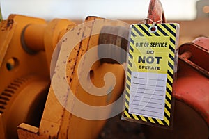Yellow out of service warning tag sign attached on faulty damage defect of heavy duty lifting beam trolley photo