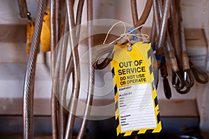 Yellow out of service warning tag sign placing on damaged faulty unsafe to use industrial fall arrest industrial hard links