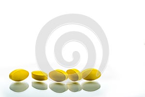 Yellow oval tablet pills with shadows on white background with beautiful creative pattern and copy space for text. Mild to moderat