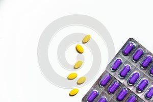 Yellow oval tablet pills on white background and purple caplets pills in blister pack. Mild to moderate pain management.