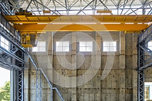 Yellow overhead crane on beam trestle in span of industrial building