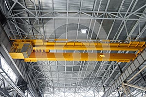 Yellow overhead crane in long span of engineering plant shop