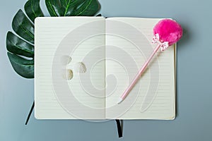 Yellow page notebook with pink pen and shell