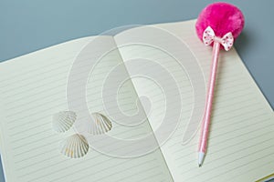 Yellow page notebook with pink pen and shell