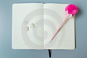 Yellow page notebook with pink pen and shell