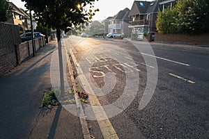 Yellow painted bus stop sign on a residential road on a summer evening as the sunlight shines though the leaves of a roadside tree