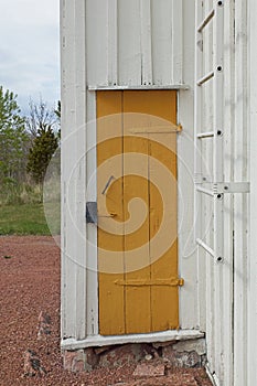 Yellow painted door on a old white wood building.