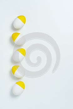 Yellow painted easter eggs aligned in a row on white background