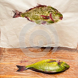 Yellow painted fish and its print on fabric