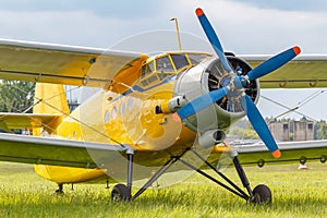 Yellow painted legendary soviet aircraft biplane Antonov AN-2 parked on a green grass of airfield closeup