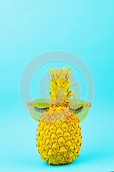 Yellow painted pineapple in sunglasses with artificial lashes. Humour, summer patry concept