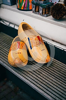 Yellow pair of traditional Dutch wooden shoes on a wooden bench