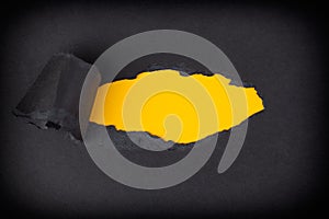 Yellow paper background appearing behind torn black paper photo