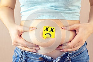 A yellow paper blank message is drawn: a sad face on belly fat with hands squeezes at the waist of a young woman in jeans.