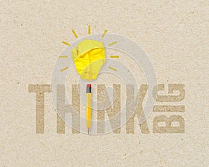 Yellow paper light bulb metaphor for creative and think big with pencil on brown recycled background
