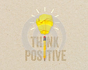 Yellow paper light bulb metaphor for creative and think positive with pencil on brown recycled background