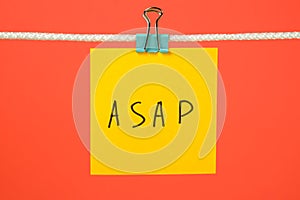 Yellow paper note on the string with text ASAP