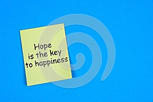 A yellow paper note with words Hope is the Key to Happiness