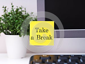 Yellow paper note with words Take a Break sticked on to a monitor at an office workplace