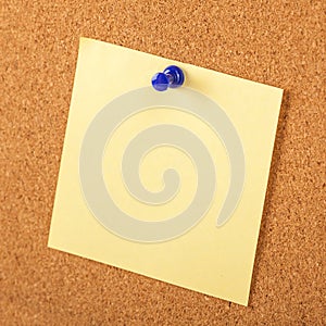 Yellow paper pined with blue tack on brown cork board background photo