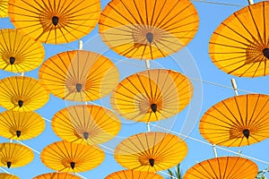 Yellow paper umbrella floating in the blue sky.