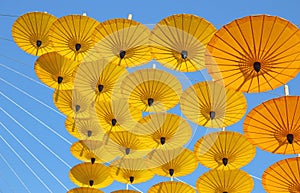 Yellow paper umbrella floating in the blue sky.