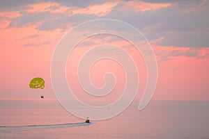 Yellow parasail wing pulled by a boat on beautiful pink sunset photo