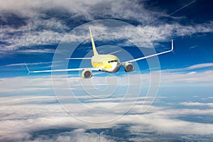 Yellow passenger jet plane in the sky. Airplane flies high through the clouds. Front view