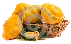 Yellow pattypan squash with leaf and flower in a wicker basket isolated on white background