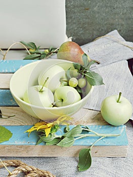 Yellow pears, apples, plums, fresh flowers, leaves, seasonal composition on a light background