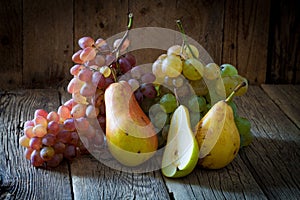yellow pears and branch of ripe organic grapes on wooden background
