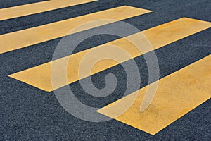 Yellow pedestrian crossing on black pavement