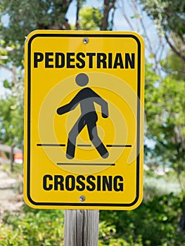A yellow pedestrian crossing sign on nature backgroud