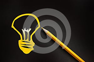 Yellow pencil and hand drawn a light bulb on black background, creative innovation idea symbol concept