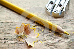 Yellow pencil and shavings on wooden background