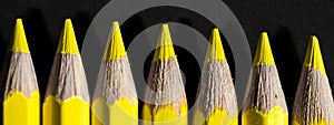 Yellow pencils all lined up on the dark black background.